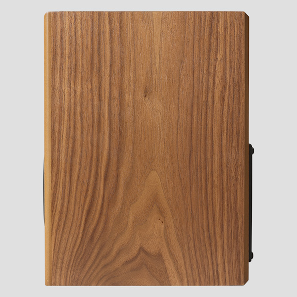 The Loon seen from the side - one uninterrupted black walnut panel with the grain running top to bottom, the black magnetic grille just visible along the front edge