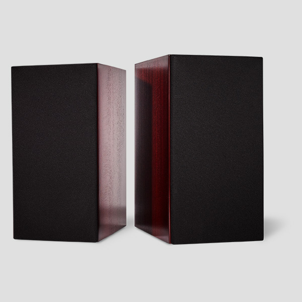 A pair of Signature One monitors in mahogany veneer with the grilles fitted, the deep red gloss of the side panels framing the black grille cloth