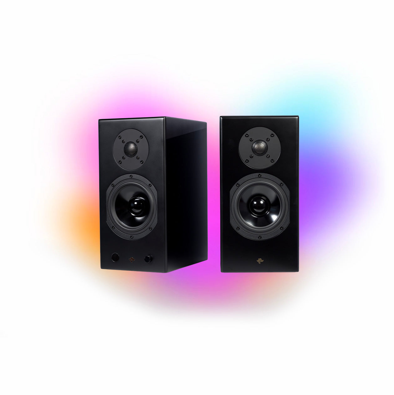 The Kin Play pair in satin black, grilles off, against a coloured glow: the active cabinet with its control knob and the passive cabinet beside it